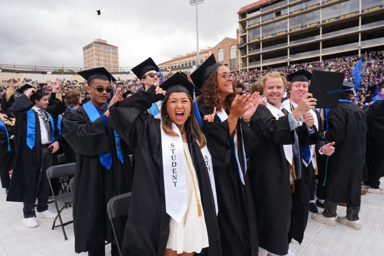 Students in regalia cheer during commencement 