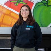 Grace poses in front of a food delivery truck in a Kobu sweatshirt.