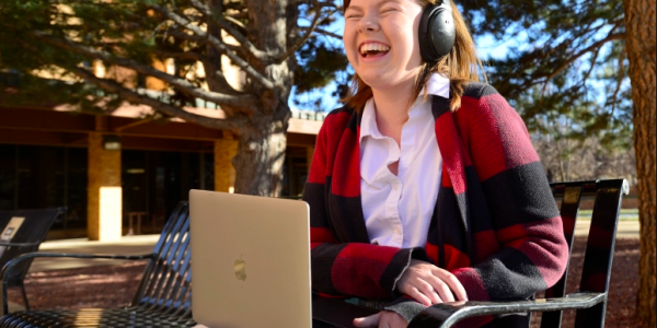 Young adult listening with headphones at laptop