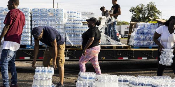 People lifting pallets of water.