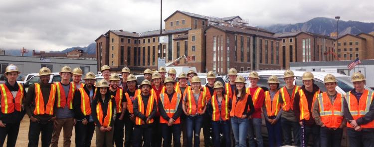 Group of people wearing construction vests and helmets.