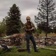 Brad Wham in a hard hat in a neighborhood burnt by the Marshall Fire
