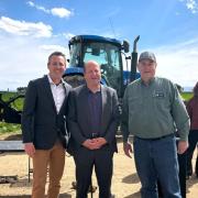 Prof. Evan Thomas with Governor Polis and an unidentified farmer in front of a tractor.