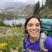 Meg Parker with a backpack on in front of an alpine lake.