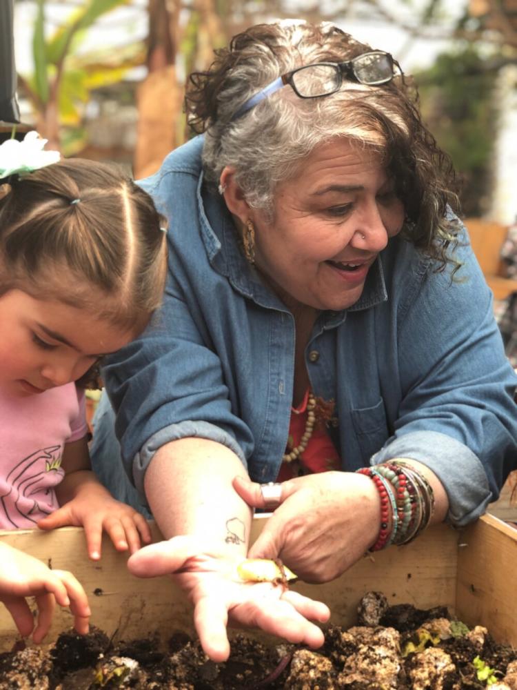 Isabel Sanchez shows a child at the Mapleton Mobile Home Park some seedlings growing