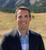 Dr. Evan Thomas smiling in front of the Flatirons