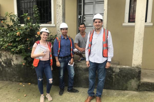 Graduate student wearing construction gear stands with project engineers
