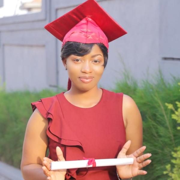 Woman in red cap and gown holding a diploma