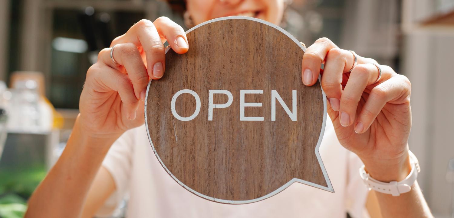 woman holding a wooden open sign