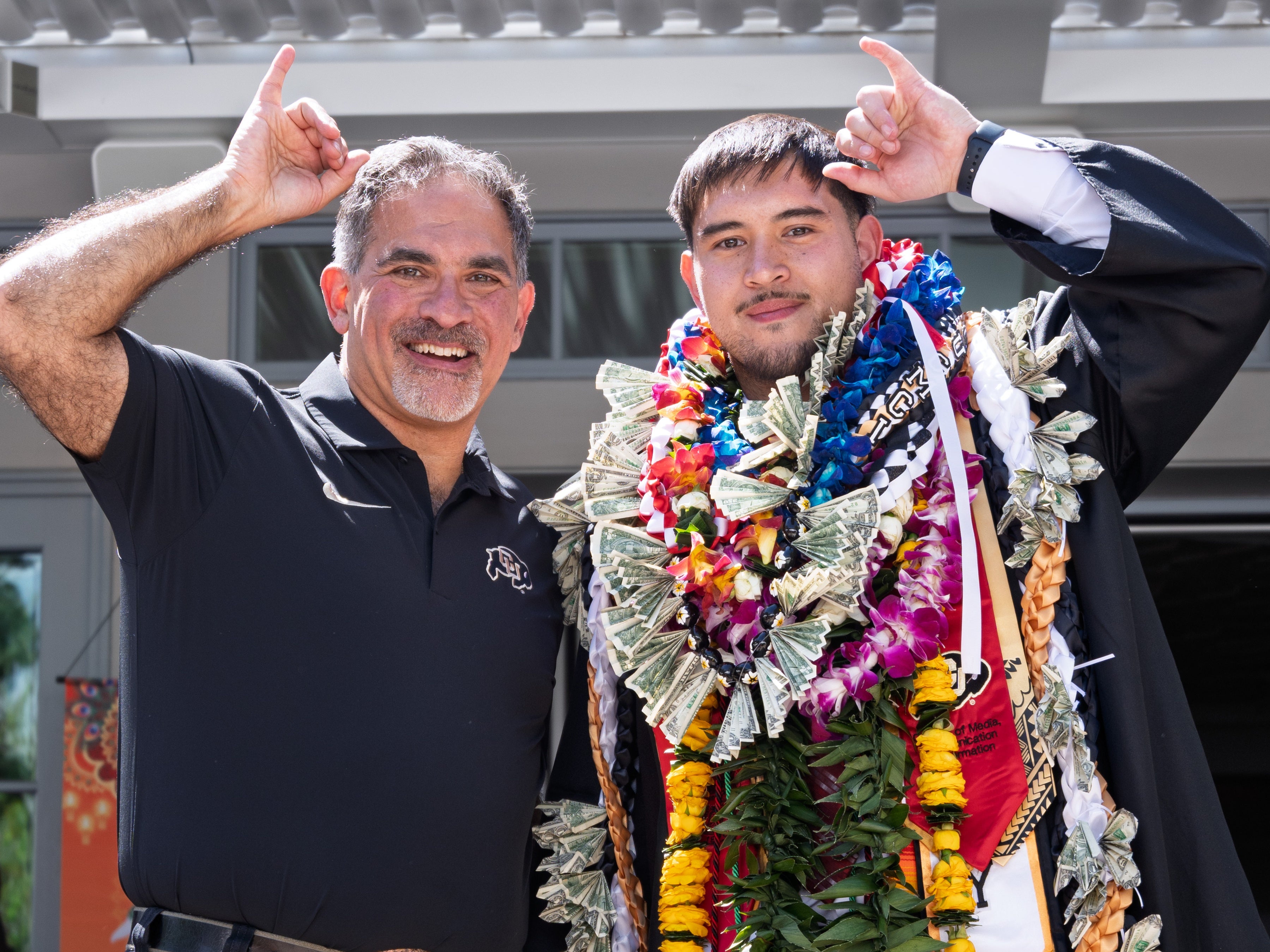 Chancellor Justin Schwartz poses with a graduate and holds up “buffalo horns” at the Asian American and Pacific Islander (AAPI) graduation celebration at Koenig Alumni Center