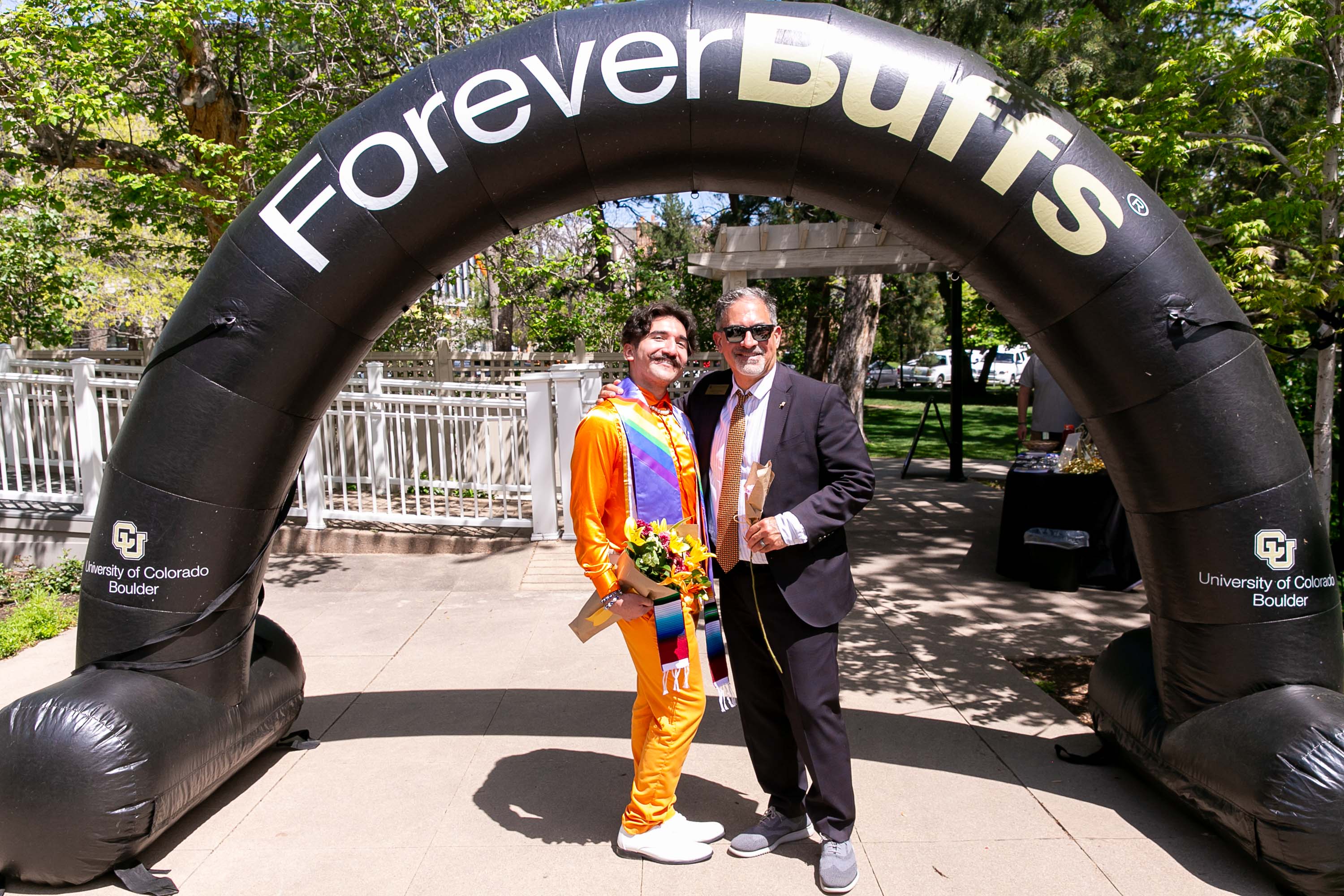 Chancellor Justin Schwartz posing with a student under a ForeverBuffs archway