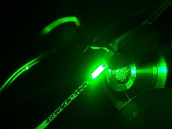 A pipette tip prototype illuminated by green light