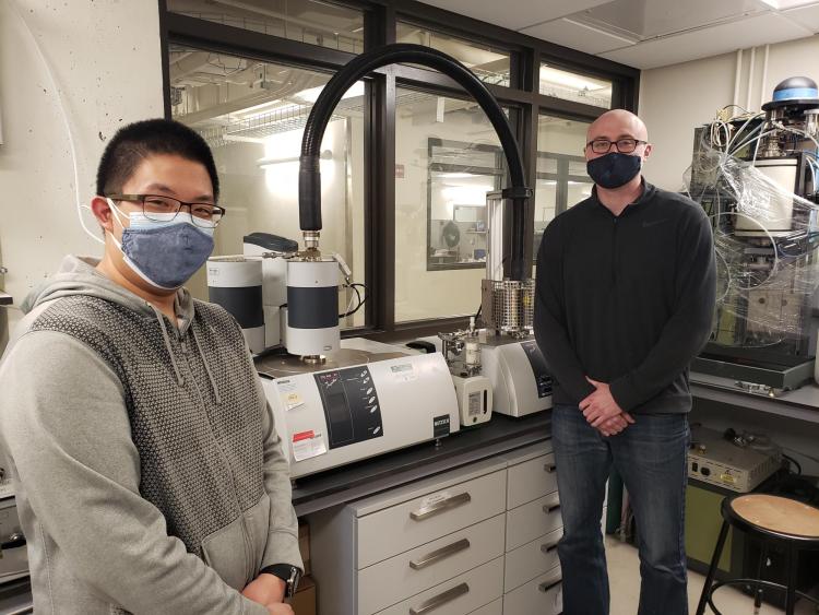 Justin Tran and Kent Warren pose in front of lab equipment