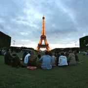 Group of students sitting on the ground near the Eiffel Tower.