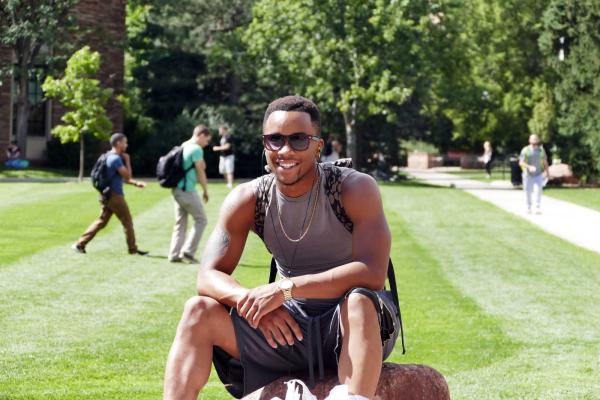 Young man sitting on CU Boulder's campus 