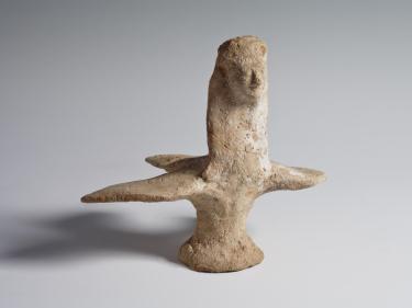 Photograph of terracotta harpy figurine, with a bird body and a human woman's neck and head, angled to viewer's right, against a neutral gray background
