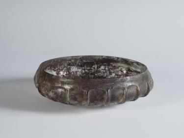 Photograph of a dark glass bowl, from a slightly raised angle against a neutral gray background.