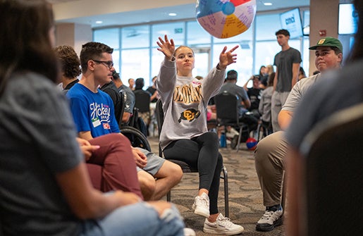 Students in a circle toss a beach ball back and forth during orientation.