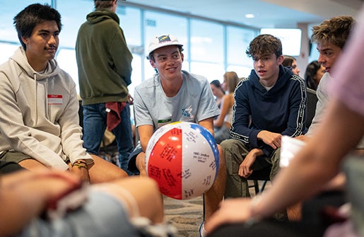 A student holds a beach ball while answering a question at orientation.