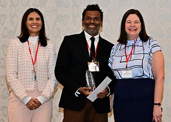 Harsha accepting his award from two presenters at the event.