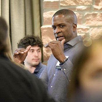 A male alumnus speaks to a group of students during a break in the agenda.