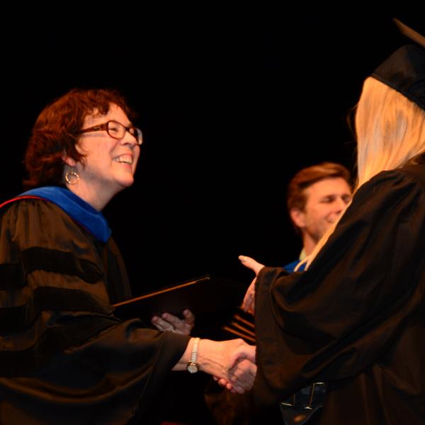 Professor shakes hand with graduating student