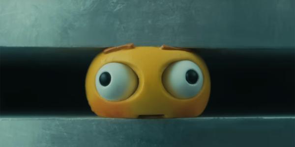 An emoji is squeezed by an industrial press in a still from Apple's controversial new ad.