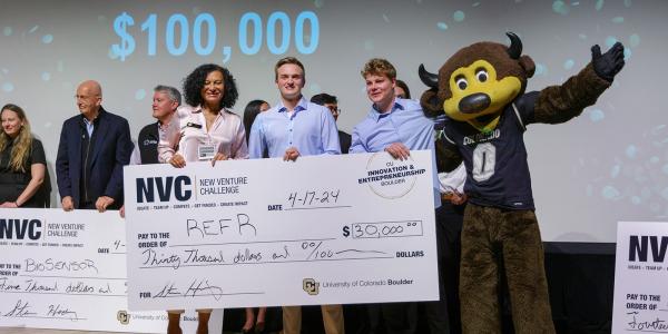 The Refr team poses with Chip, the Buffaloes mascot, and an oversize winning check on a stage.