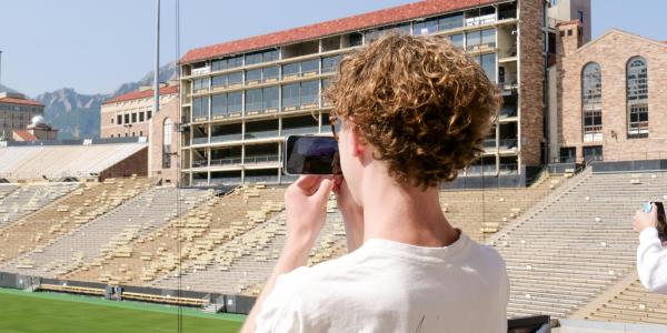 Student taking photo of Folsom Field