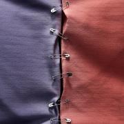 Blue and red swatches of cloth held together by safety pins.