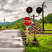 A railroad crossing through a rural road with a stop sign and lights.