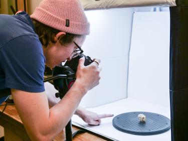 Student taking a photo of a fossil inside a light box. 