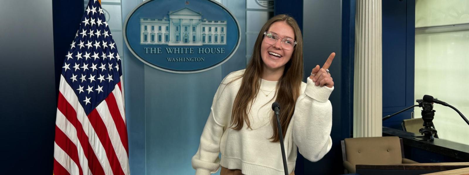 A student poses in the White House press room on a tour.