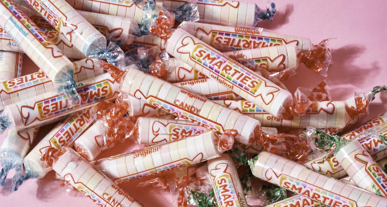 wrapped smarties candies on a pink background