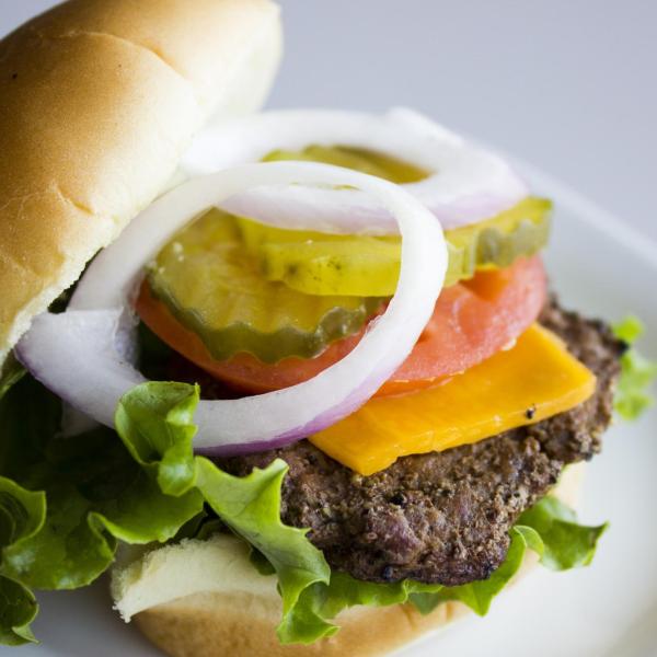 Hamburger with cheese, tomato, pickles, lettuce and onion