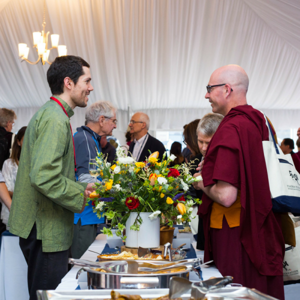 Two men talking over a flower arrangement on a catering table
