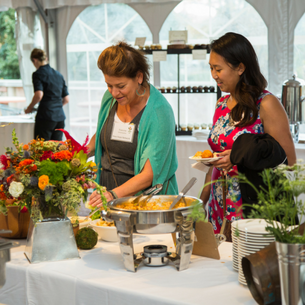Two women selecting food on a buffet