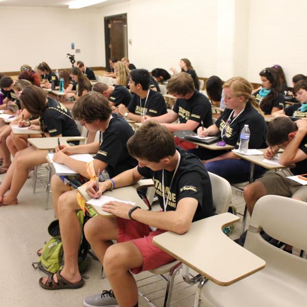 Camp attendees taking notes at desks in academic classroom