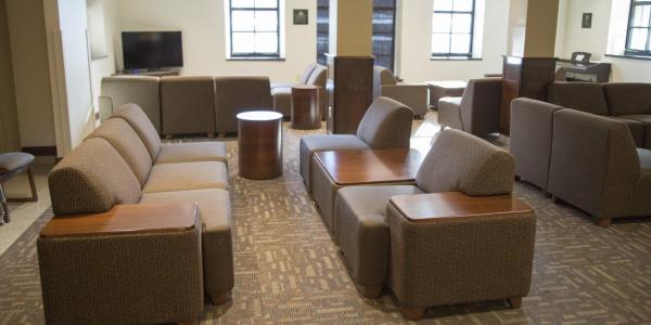 Baker lounge area with modular furniture, round side tables, carpeted floors, windows, tv