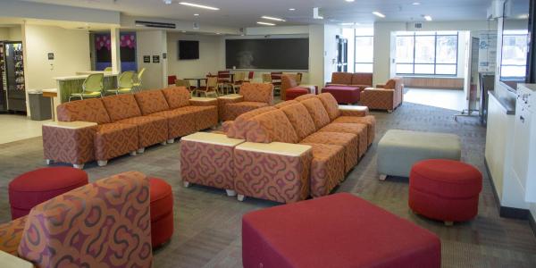 Kittredge West lounge area with multi-patterned modular furniture and foot stools, windows, carpeted floors