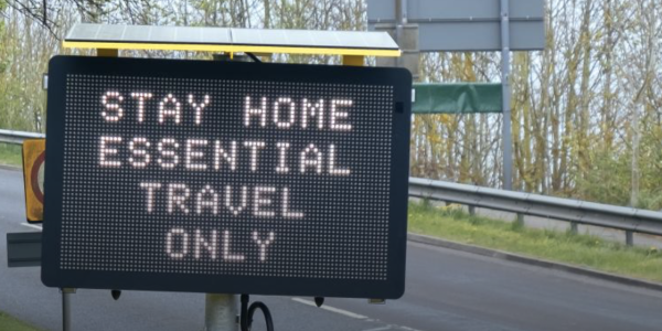 Road sign with text Stay home essential travel only