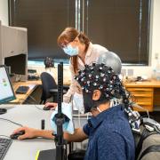 Rosy Southwell and Cooper Steputis demonstrate the use of a functional near-infrared spectroscopy device in D'Mello's lab