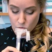 A researcher provides a saliva sample for a rapid COVID-19 test in a lab 