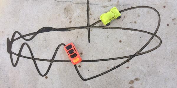 A function etched in a rock. Two toy cars drive along the line.