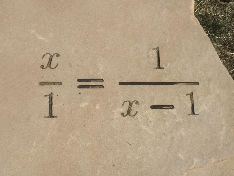 The equation x/1 = 1/(x -1) etched in stone