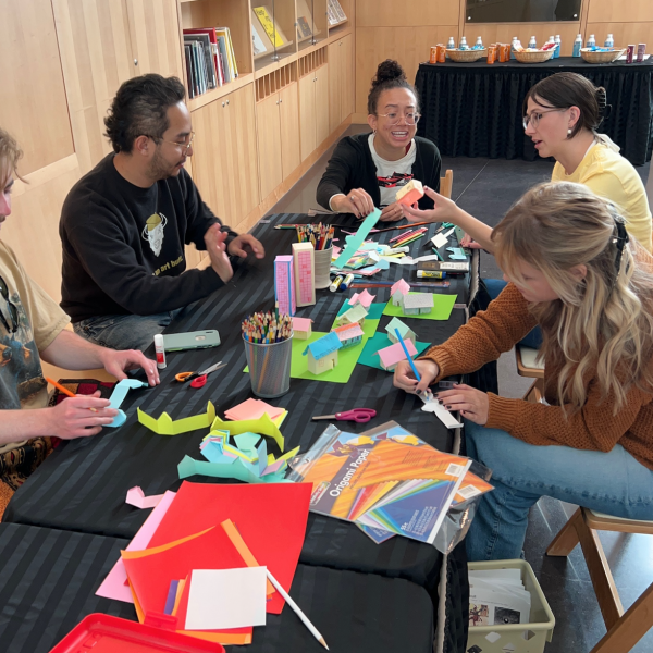 Five students making crafts at a table together in the CU Art Museum lobby.