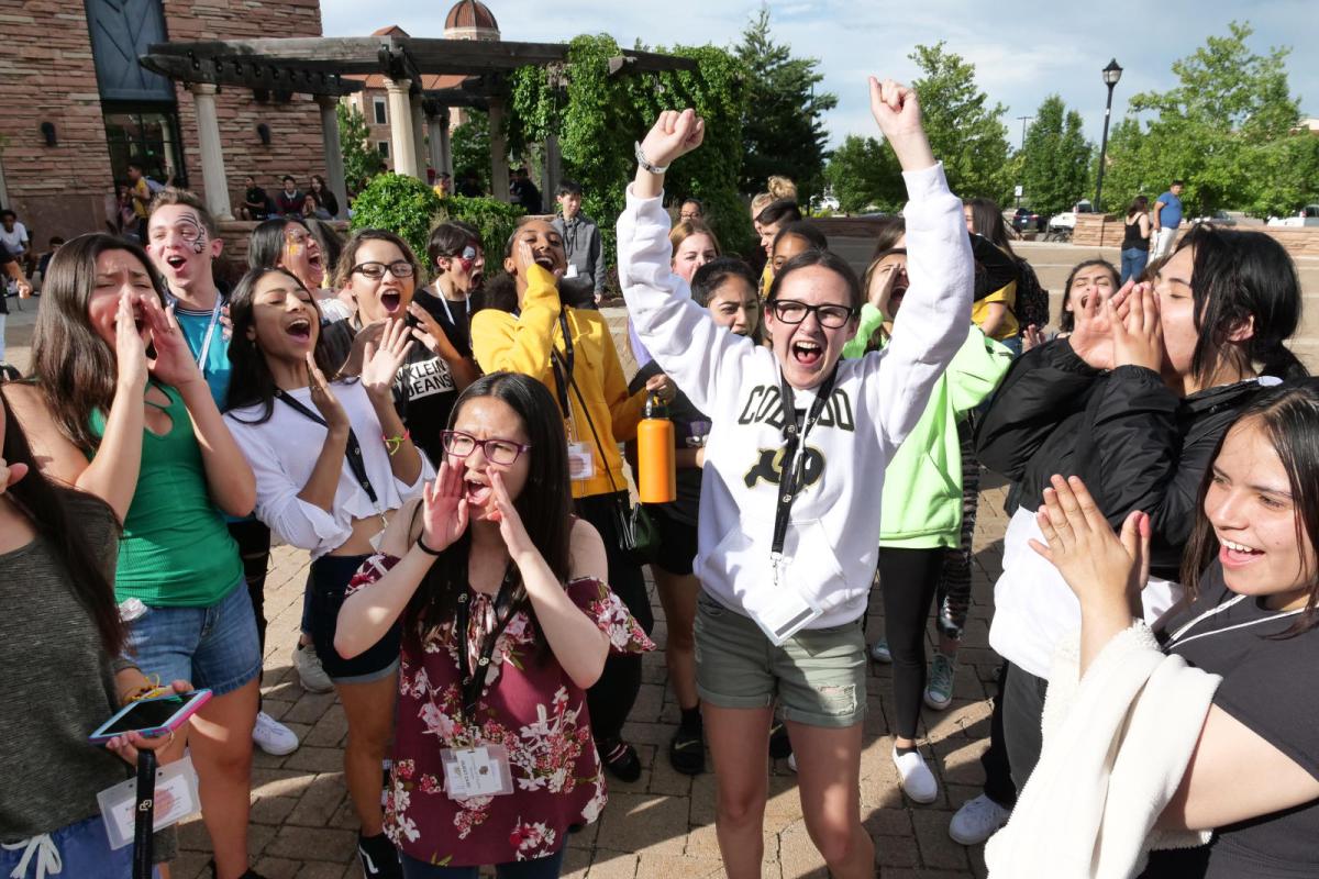 students gathered in a circle shouting and clapping