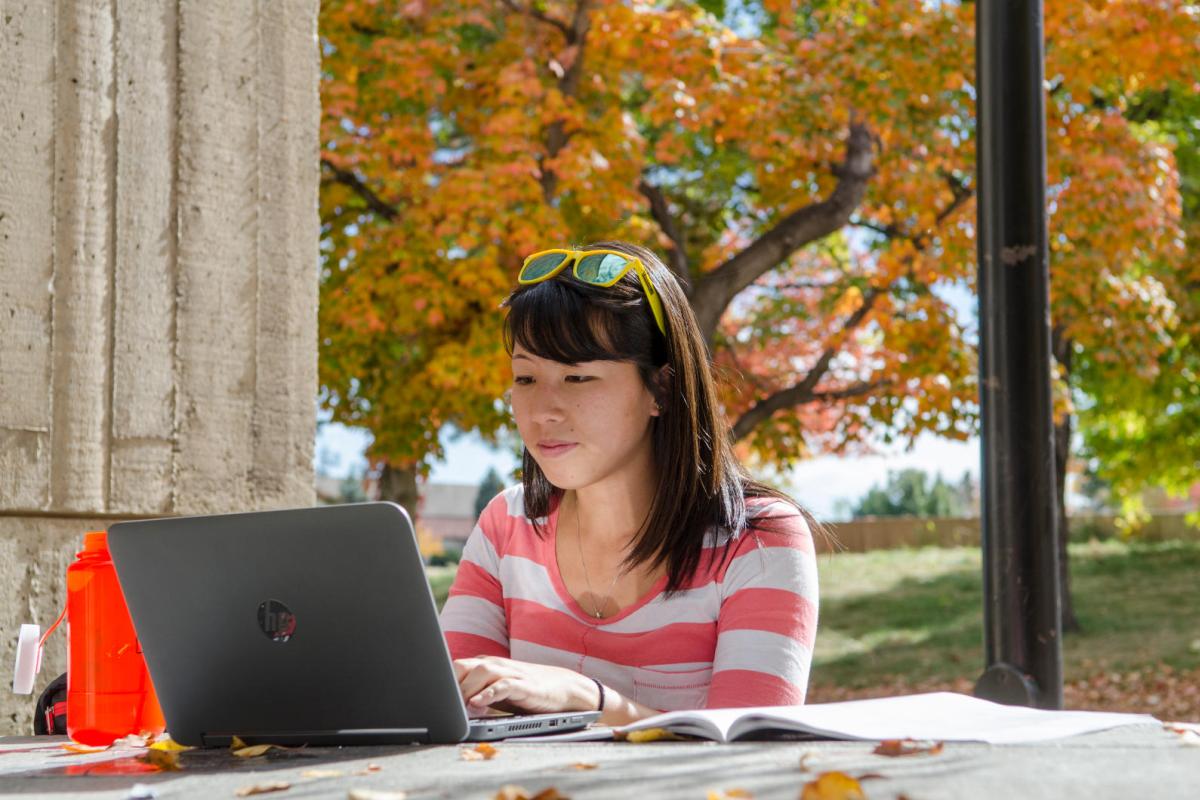 student sitting at a table working on her laptop