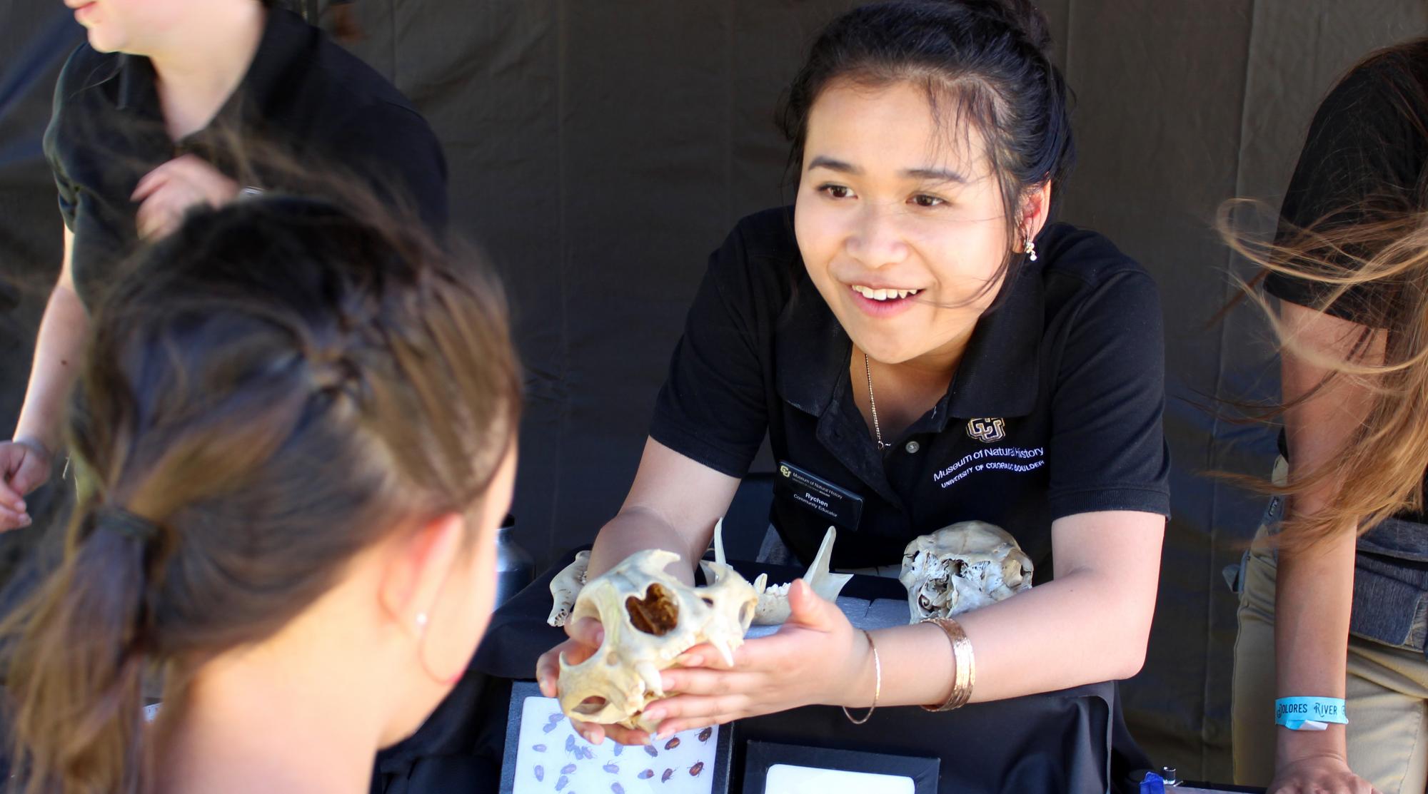 student showing animal skull to museum visitor