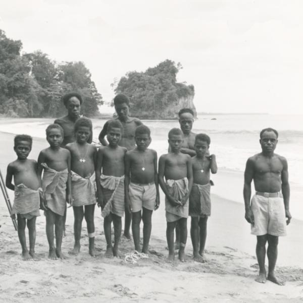 Seven young boys and three adult men on beach.